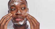 Black man cleansing and washing his face with soap